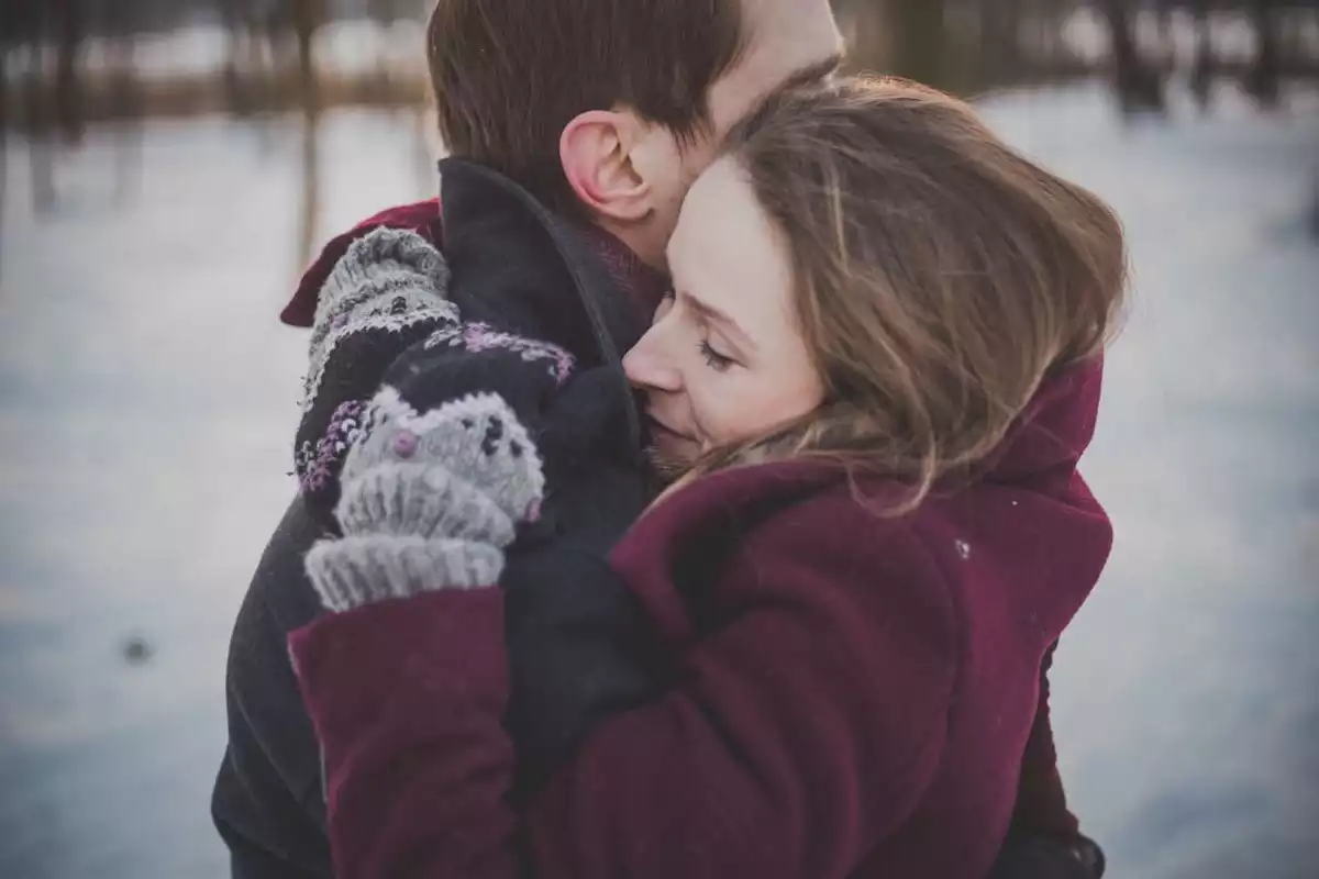 Una chica y un chico abrazándose en medio de la nieve