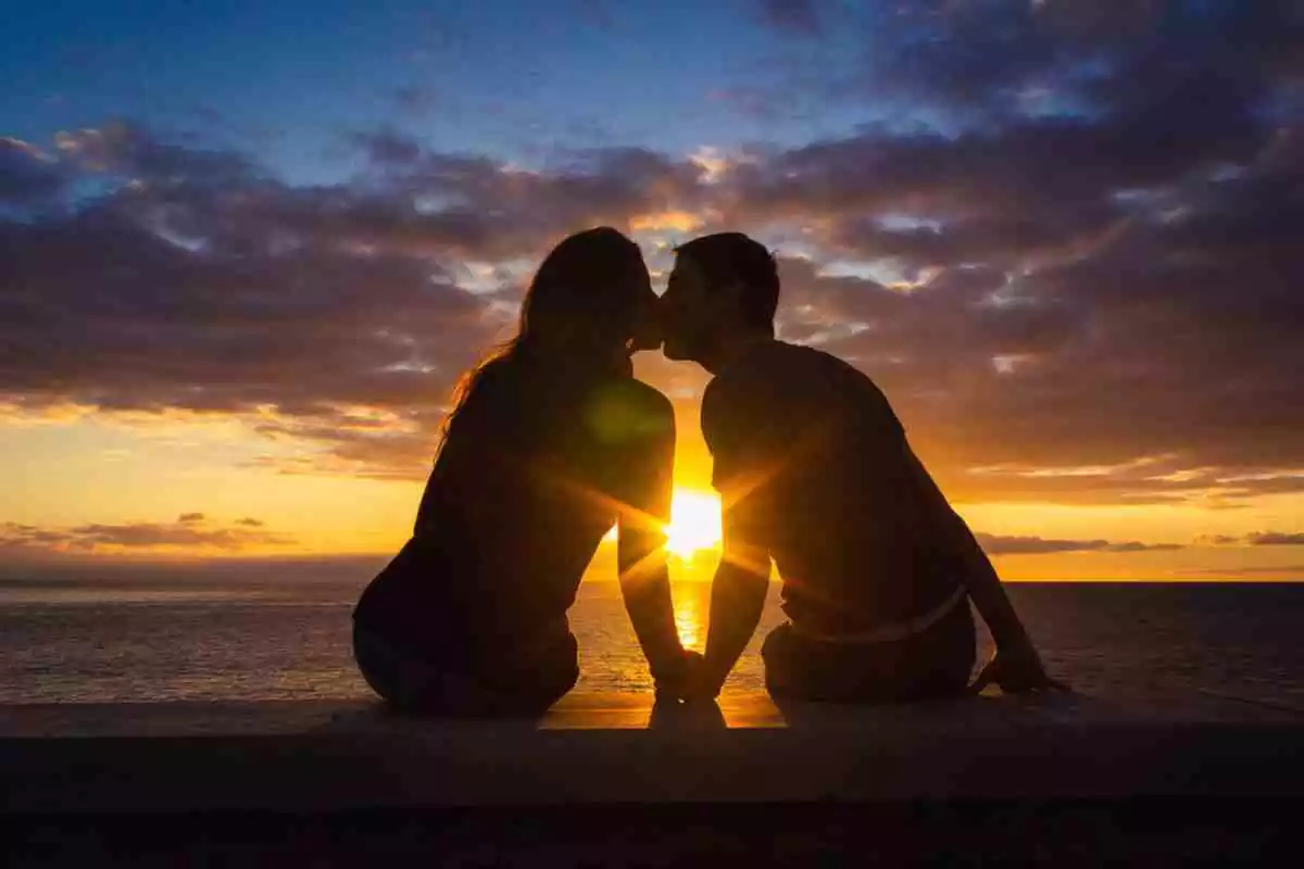 Una pareja besándose ante una puesta de sol