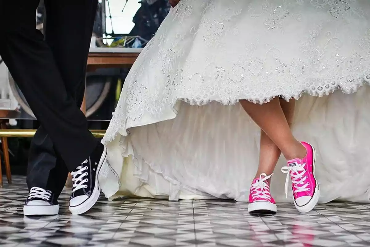 Un hombre y su mujer celebrando su boda con zapatillas a juego, de color negro y rosa