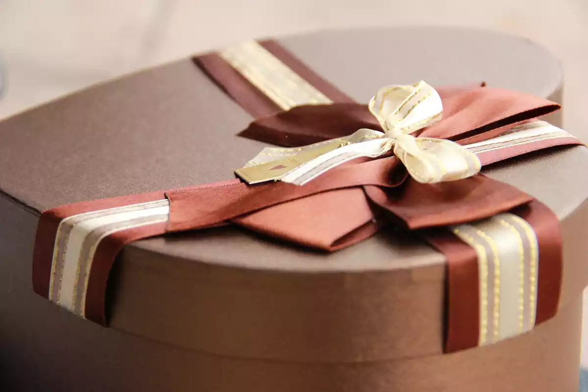 Un regalo en forma de corazón rodeado de una cinta de color marrón y blanco